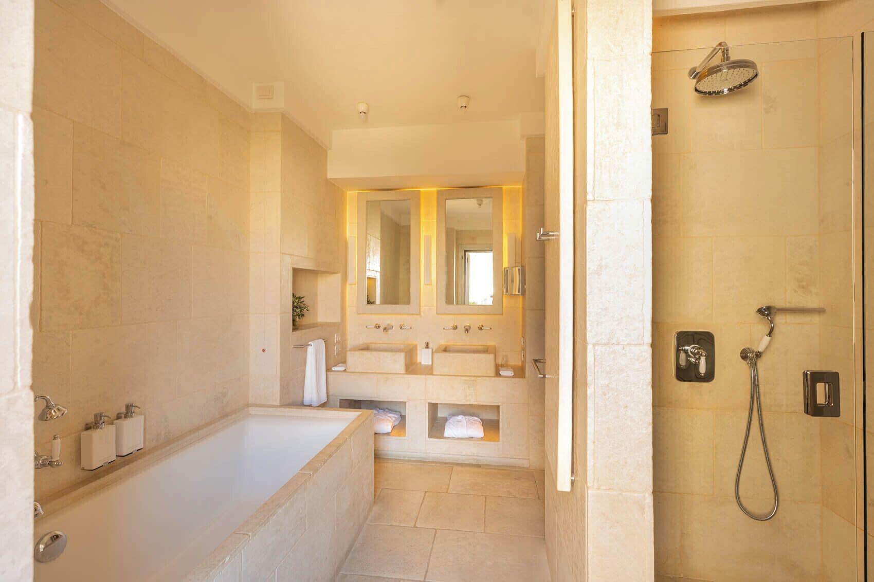 A modern bathroom with a bathtub, two sinks, a shower, and a large mirror.