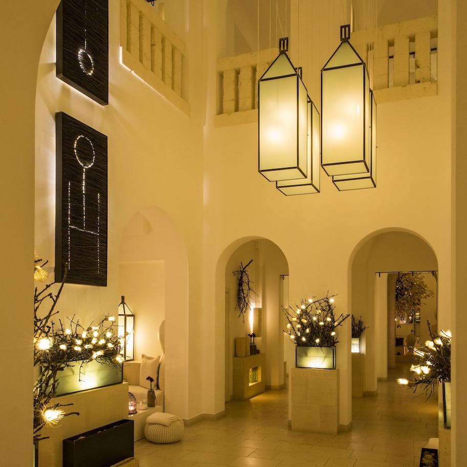 A spacious lobby with high ceilings, arched doorways, and hanging lantern-style lights.