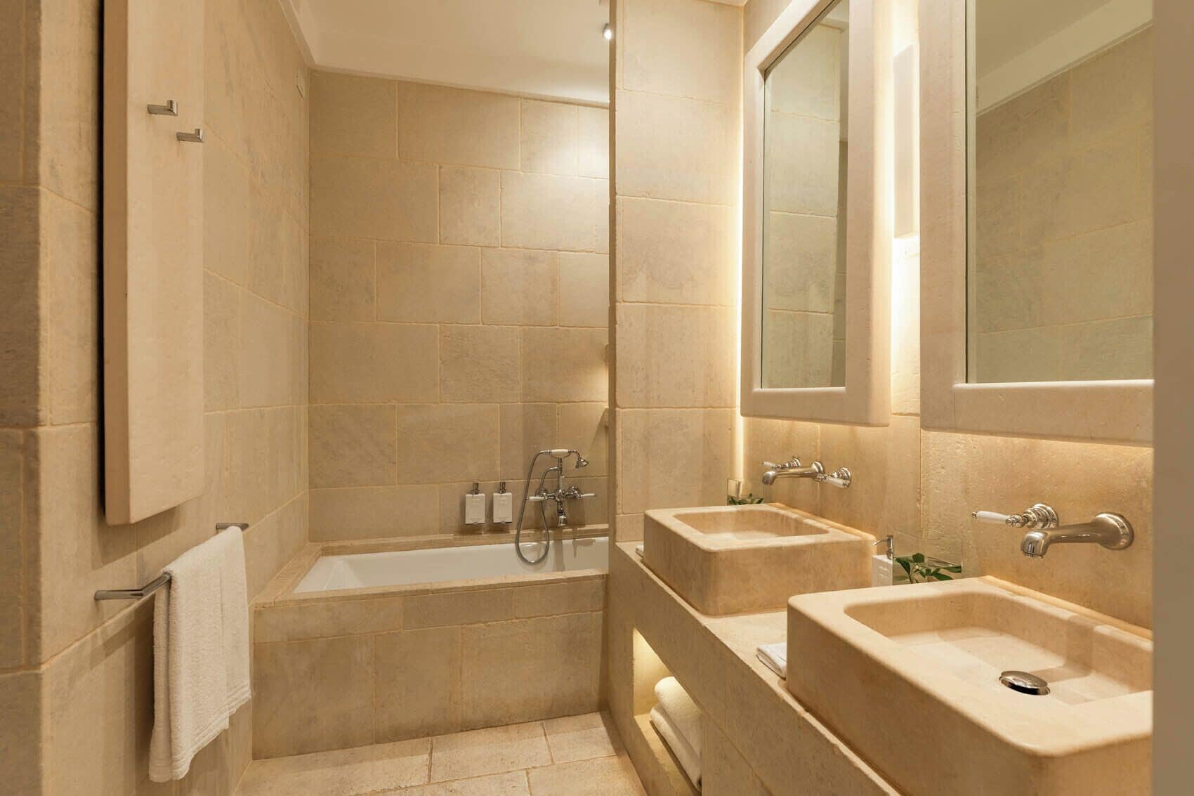 A bathroom with a bathtub, two sinks, and a mirror.