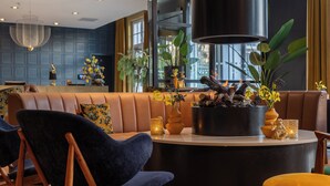 Un moderno vestíbulo de hotel con zona de estar, una recepción y grandes ventanales.