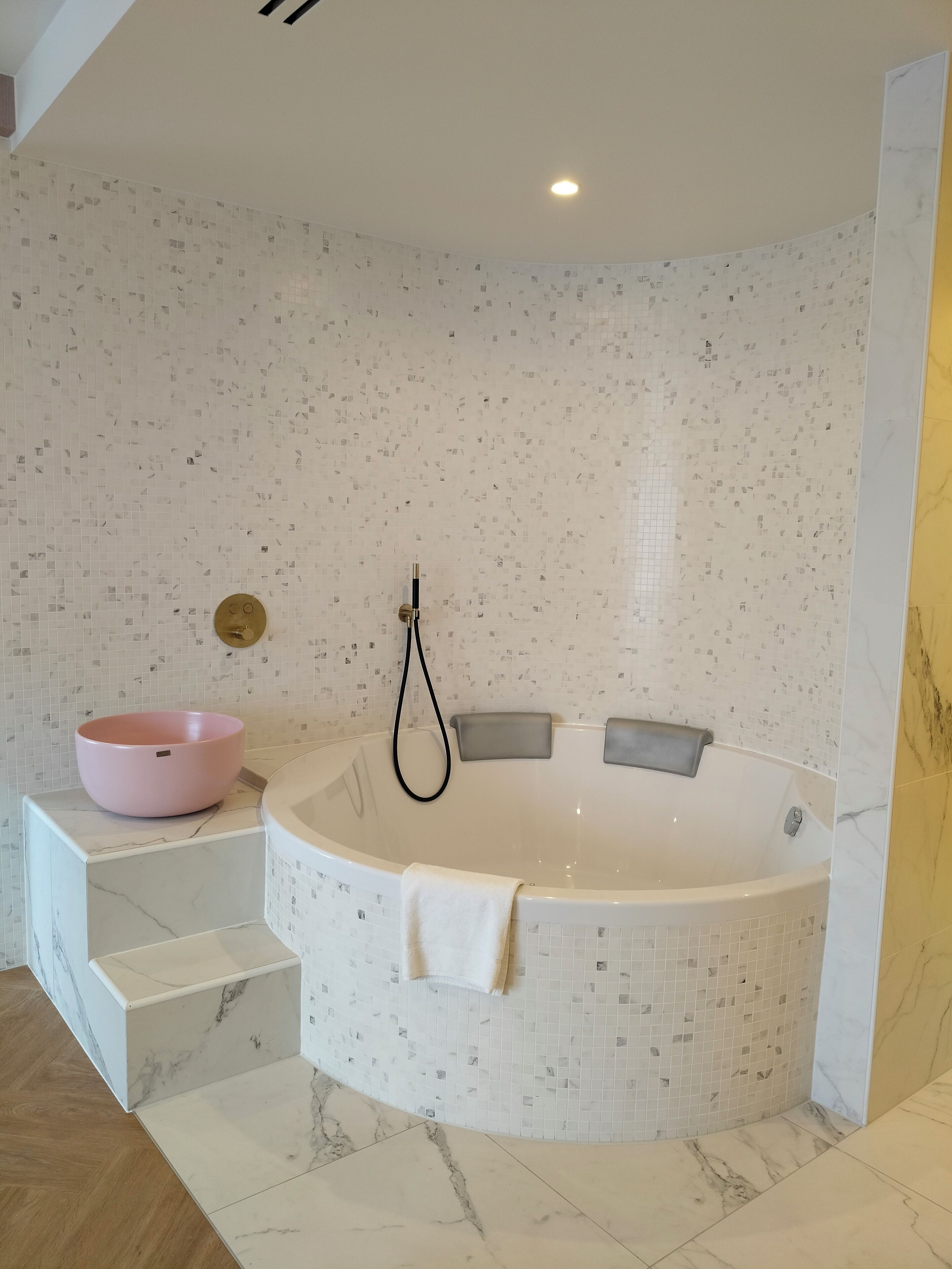 Une salle de bain moderne avec une baignoire sur pieds, un lavabo rose et un sol en marbre.