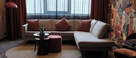 A modern living room with a sectional sofa, a coffee table, and a patterned wall.