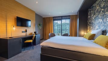 Une chambre d’hôtel moderne dotée d’un grand lit, d’un bureau avec une chaise, d’un téléviseur à écran plat et d’une grande fenêtre avec des rideaux.