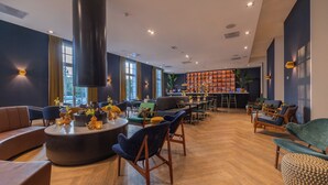 Un amplio salón con bar, zonas de estar y una planta grande.