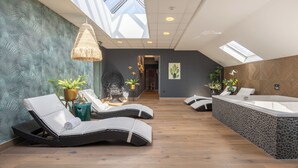 Un spa moderno con tragaluz, sillones reclinables, una bañera e instalaciones de plantas.