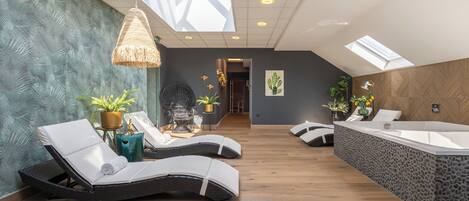 Un spa moderno con tragaluz, sillones reclinables, una bañera e instalaciones de plantas.