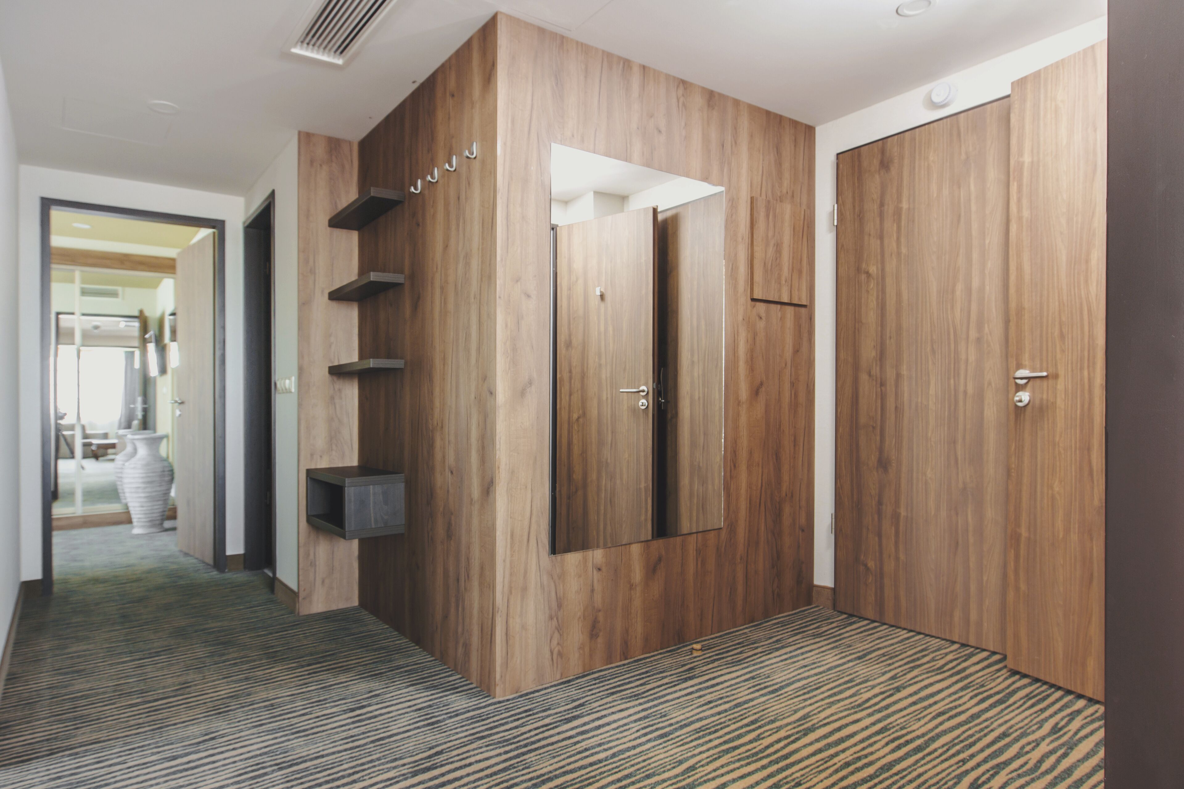 A hallway with wooden paneling, a large mirror, and a carpeted floor.