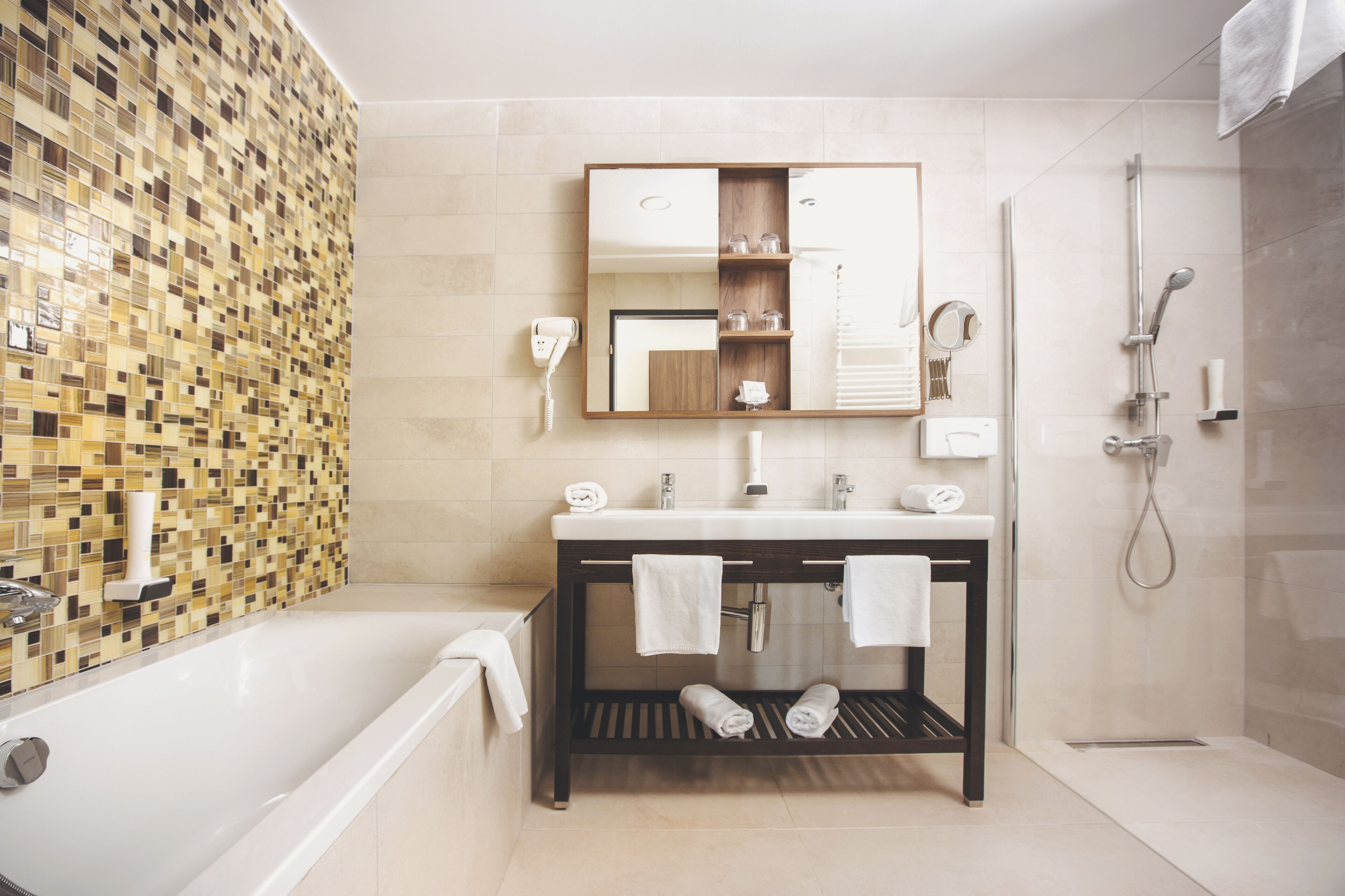 A modern bathroom with a bathtub, a vanity with a mirror, and a shower area.