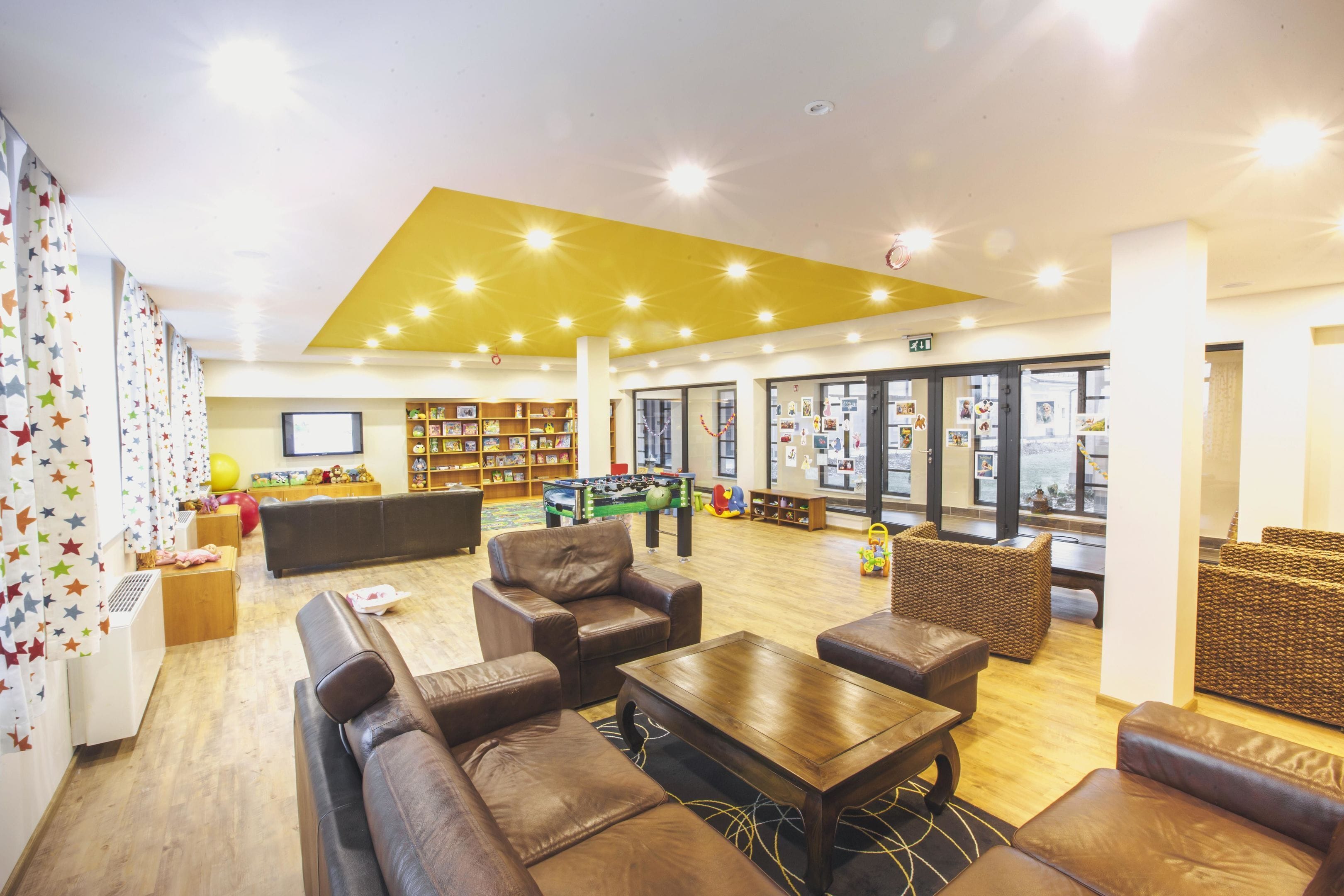 Eine großzügige Lobby mit Ledersofas, einem Couchtisch und einer Bücherwand.