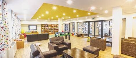 Eine großzügige Lobby mit Ledersofas, einem Couchtisch und einer Bücherwand.