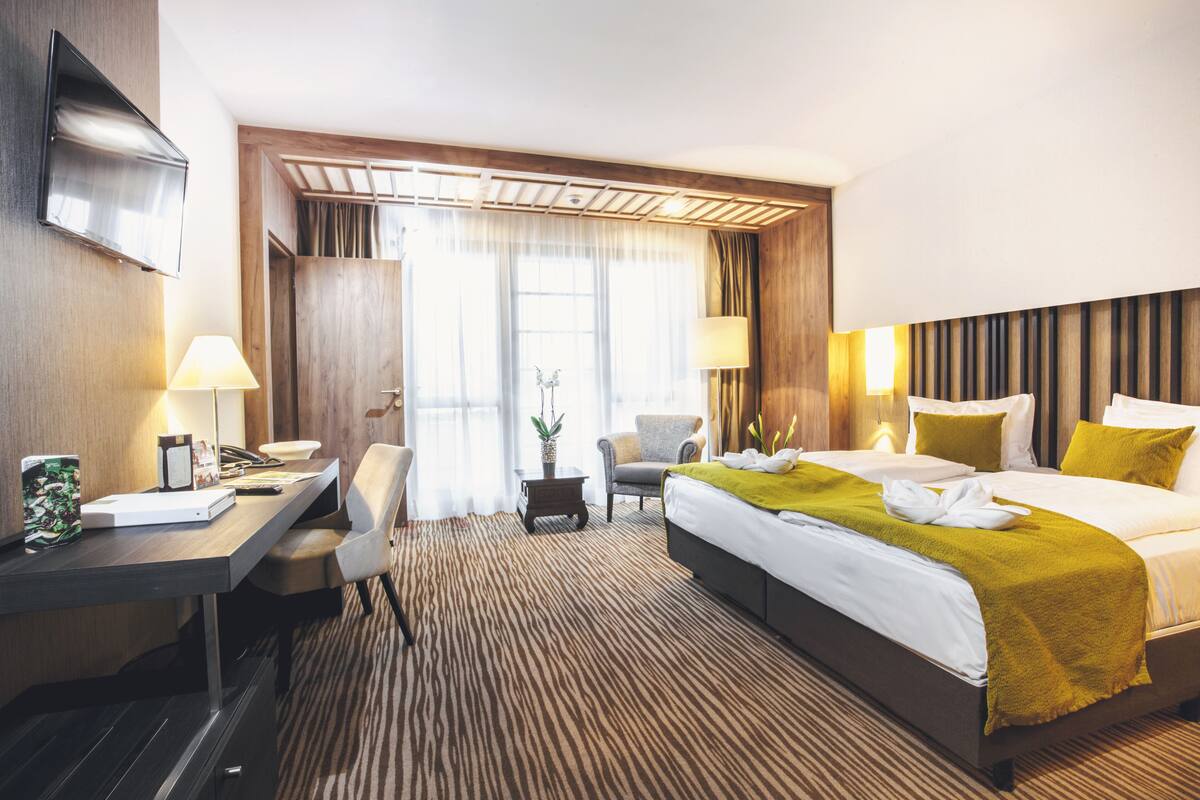 Ein Hotelzimmer mit Bett, Schreibtisch, Stuhl und Fernseher.