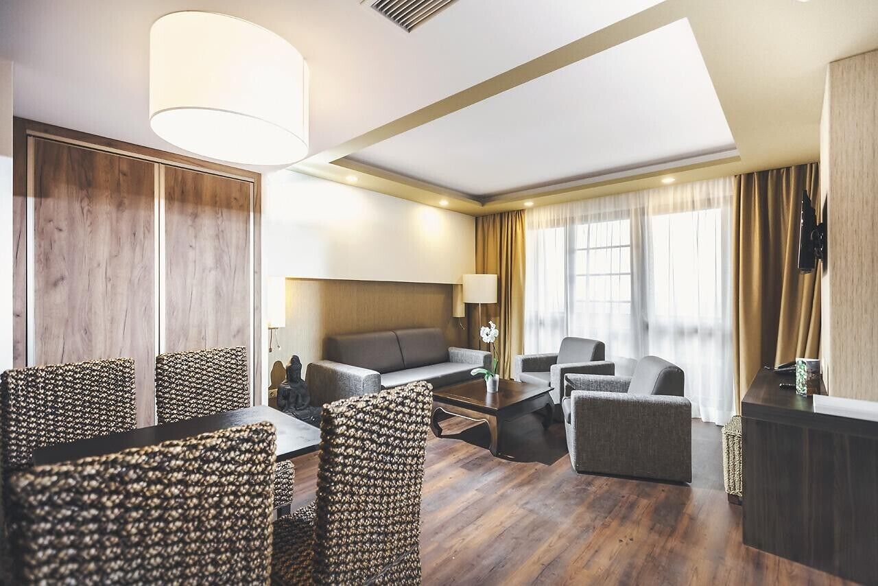 Ein Hotelzimmer mit Essbereich, Sofa und einem an der Wand befestigten Fernseher.