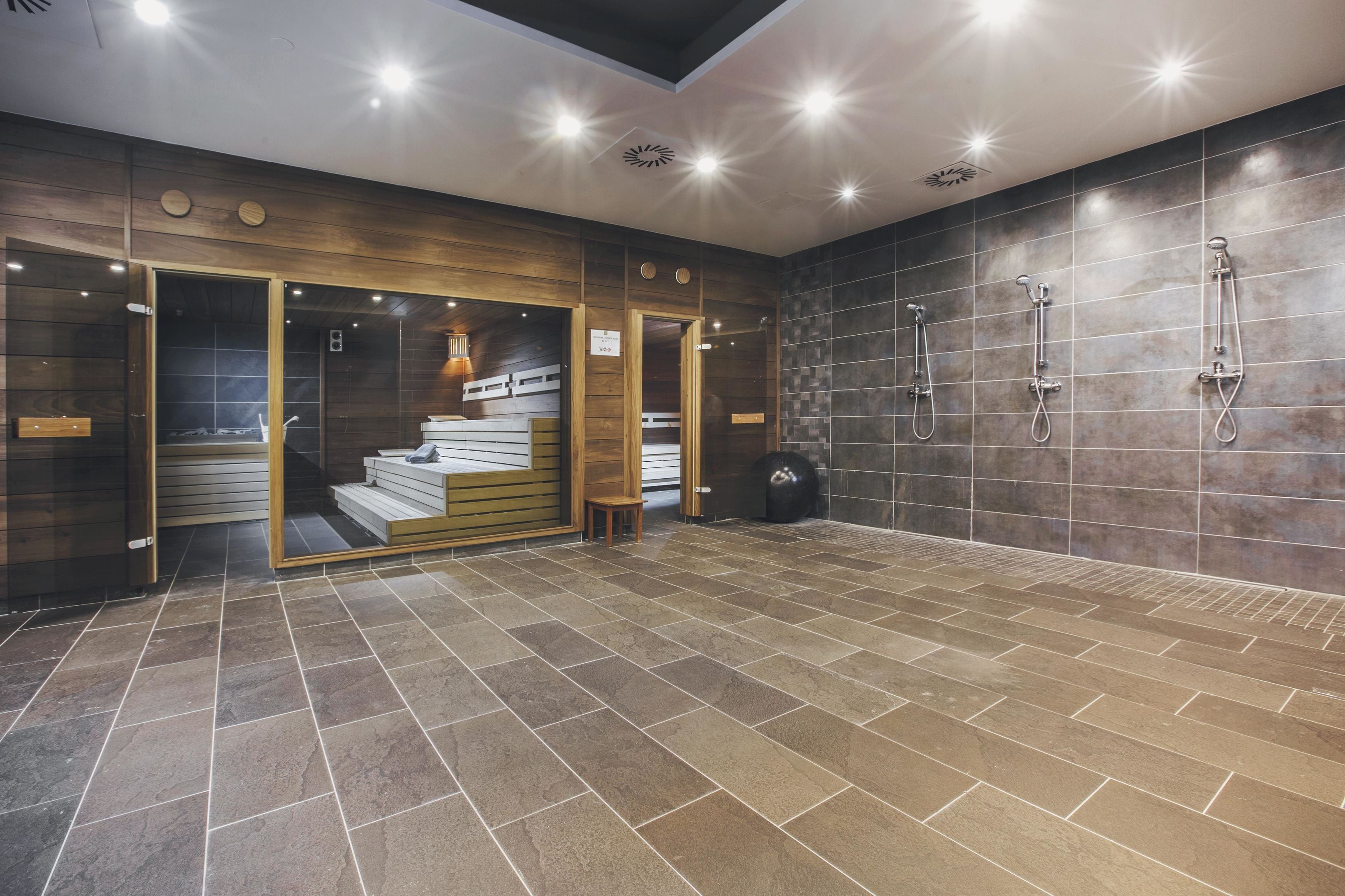 A modern bathroom with a wooden door, a shower area, and a tiled floor.