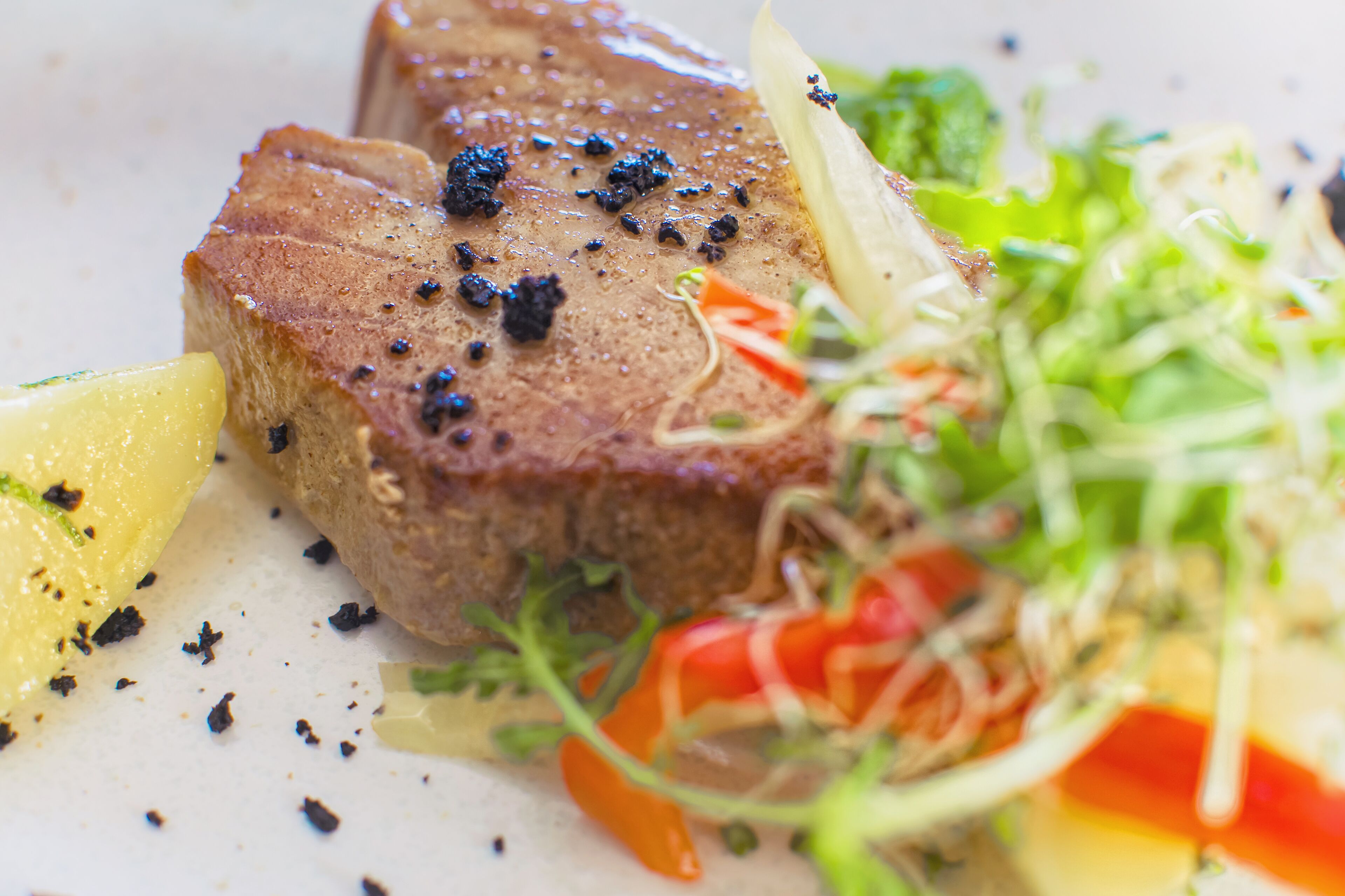 Primer plano de un bistec con pimienta negra y una ensalada al lado.