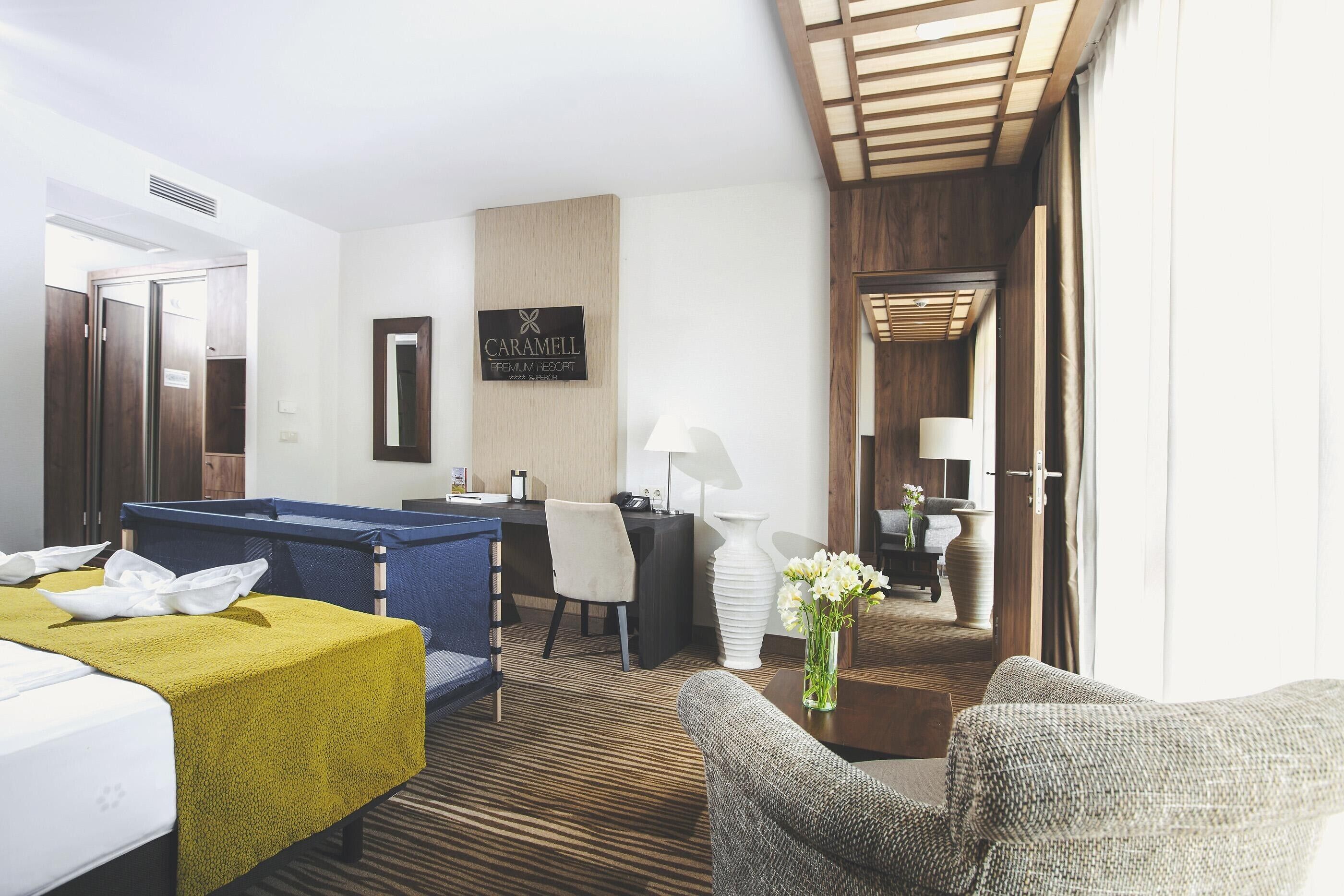 A hotel room with a bed, a desk, a chair, a sofa, and a small table with a vase of flowers.