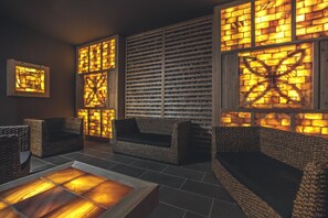 Un área de descanso moderna con sofás de mimbre, una mesita de centro y paneles decorativos en la pared.