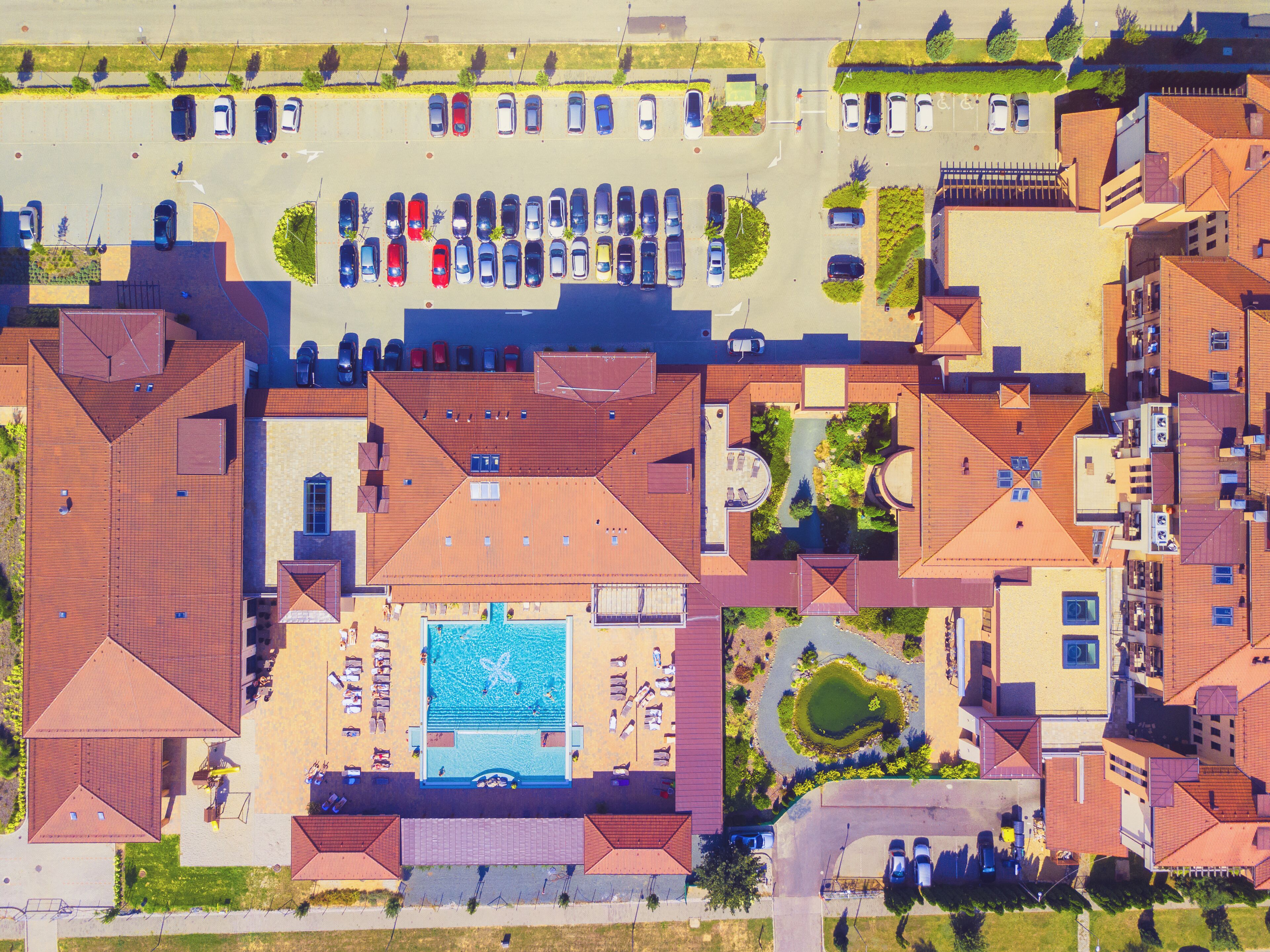 An aerial view of a residential area with multiple houses, a swimming pool, and a parking lot.