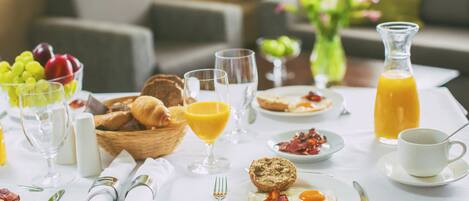 A breakfast table with various food items, including eggs, bacon, toast, and fruit.