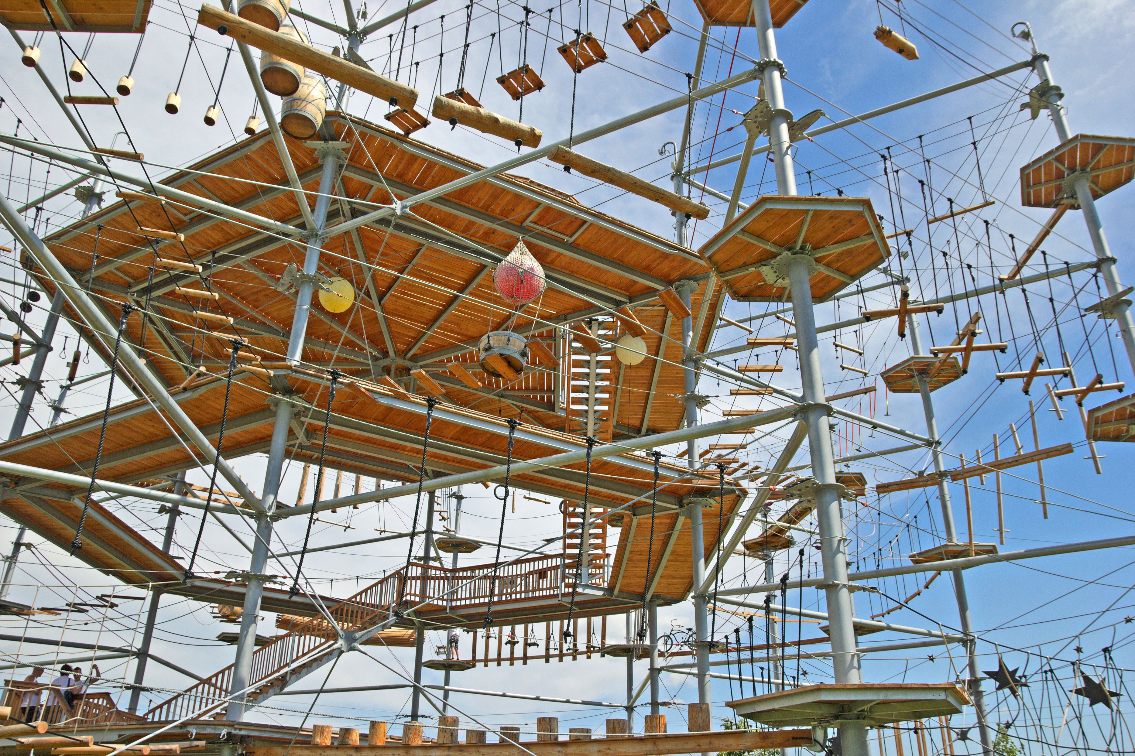 A large, complex wooden structure with multiple levels and platforms, supported by metal beams and ropes.