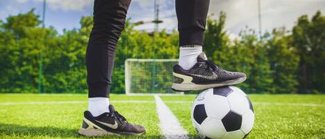 Una pelota de fútbol sobre un campo de césped con un arco de portería al fondo.
