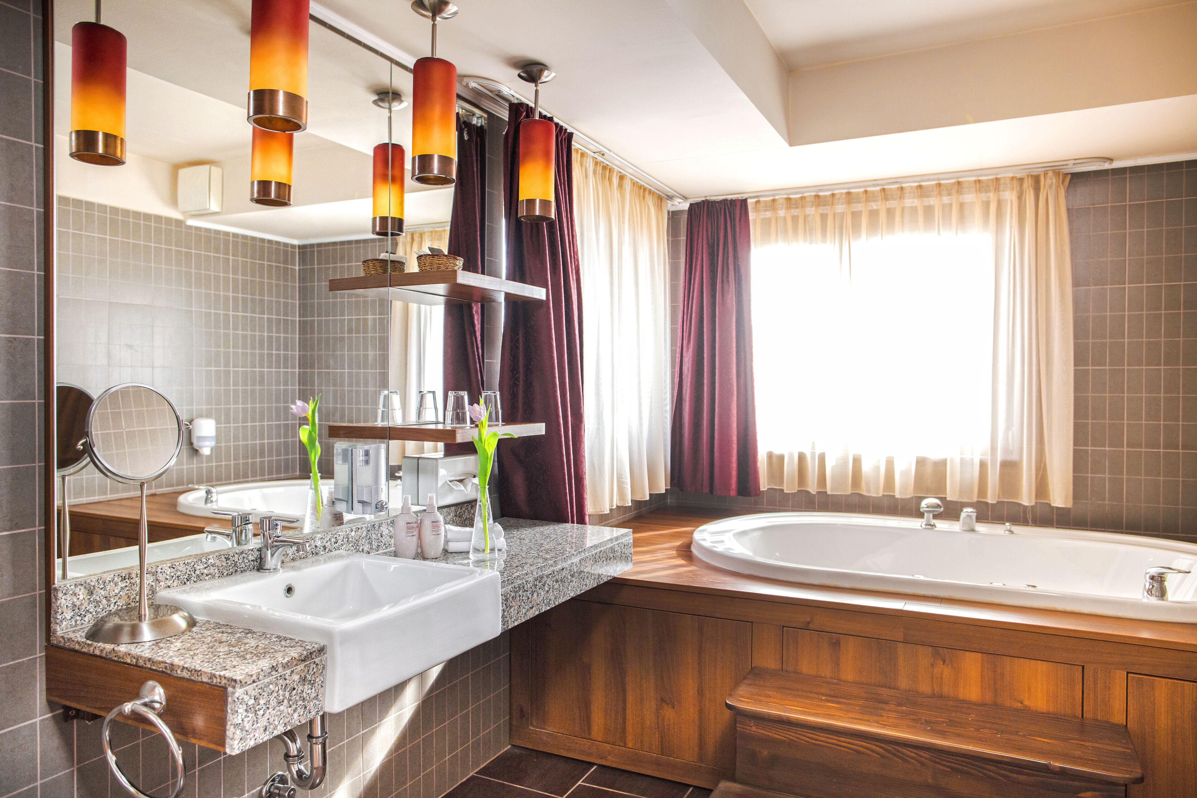 Un baño moderno con dos lavamanos, una bañera grande y un tocador con espejo.