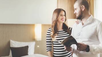 A couple in a hotel room with a bed, pillows, and a nightstand.