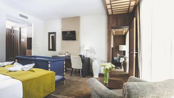 Habitación de hotel con cama, escritorio, silla, sofá, lámpara y un florero con flores.