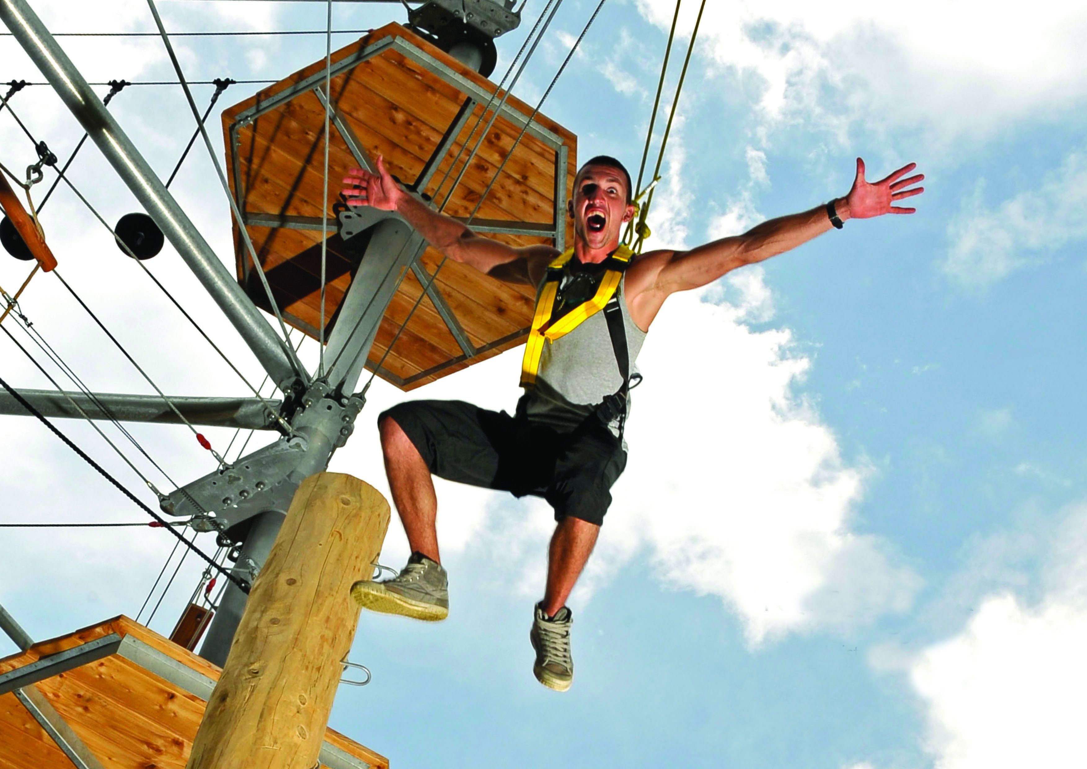 Uma pessoa faz bungee jumping presa com arnês e cordas de segurança.