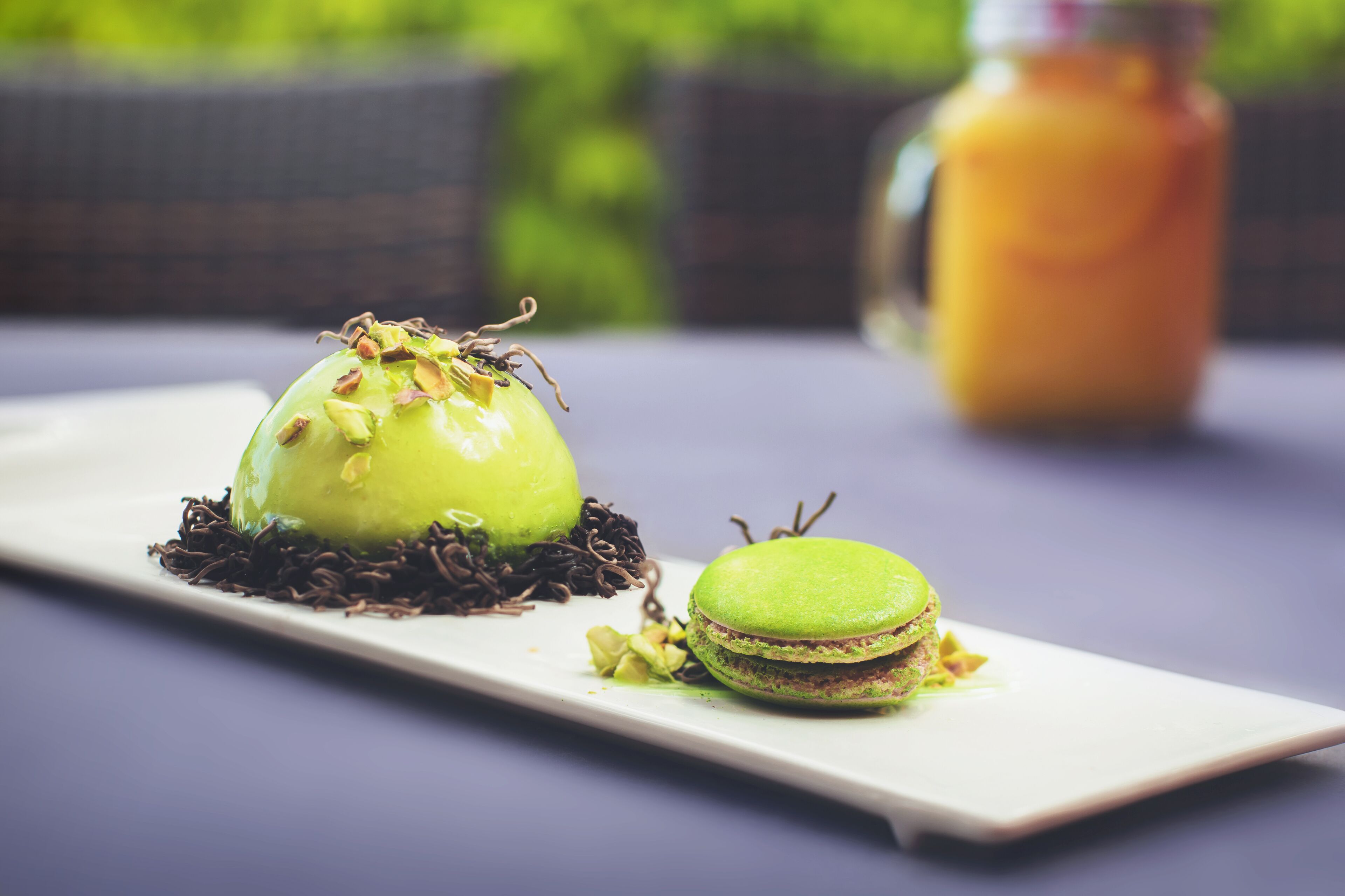 Une assiette à dessert avec un macaron vert et un autre dessert vert, le tout présenté sur une assiette blanche.