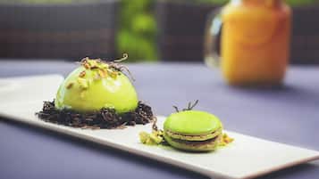 Un plato de postre con un macaron verde y un postre verde sobre una fuente blanca.