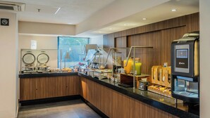 Eine moderne Frühstückstheke mit einer Kaffeemaschine, einer Obstauslage und einer Glaskonstruktion für einen Kaffeezubereiter.