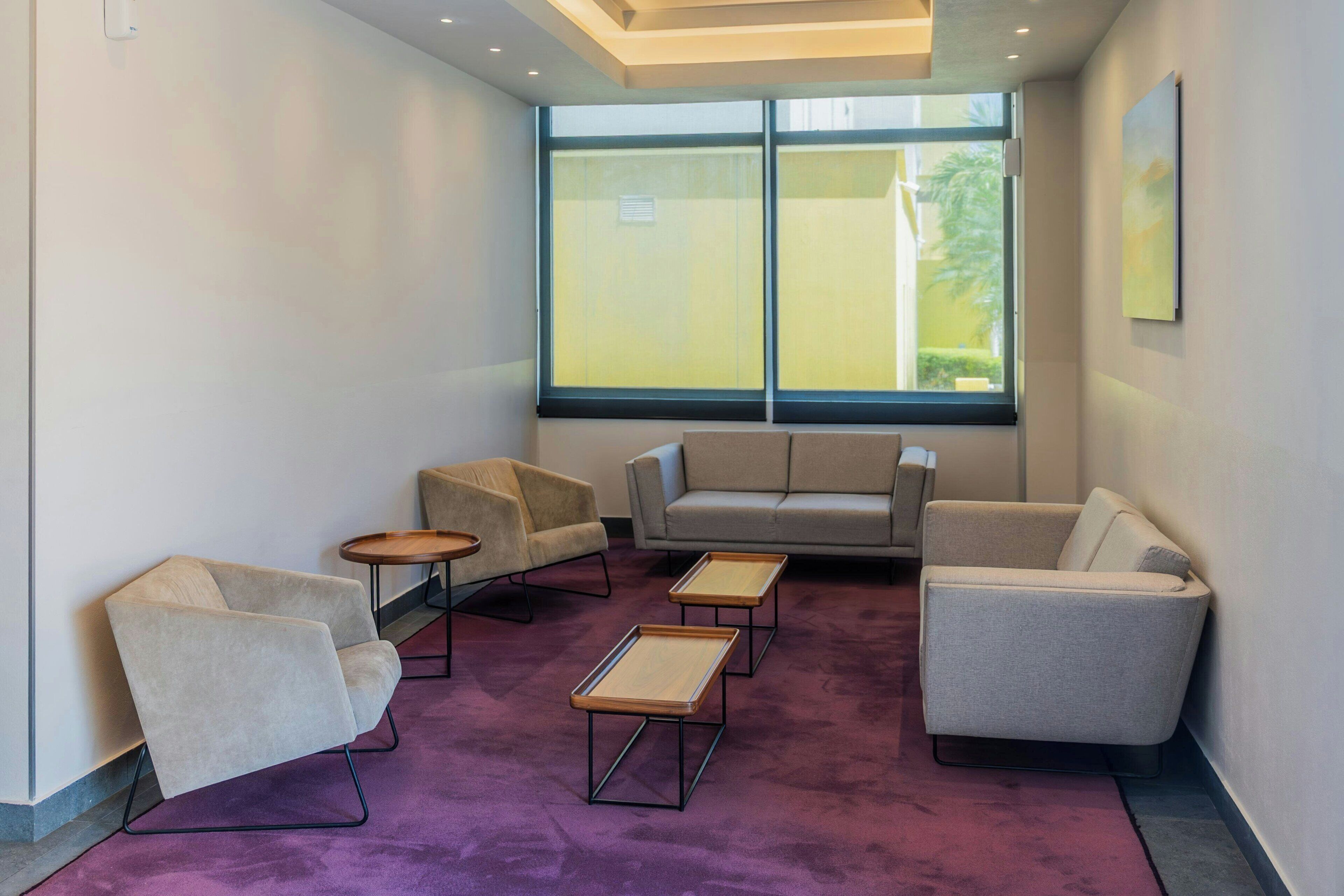 Un espace d’attente moderne, doté d’un canapé, de fauteuils et d’une table basse.