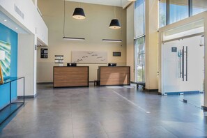 Un área de recepción de diseño moderno, con mostrador de recepción, dos lámparas colgantes, una obra de arte en la pared y un ventanal que proporciona luz natural.