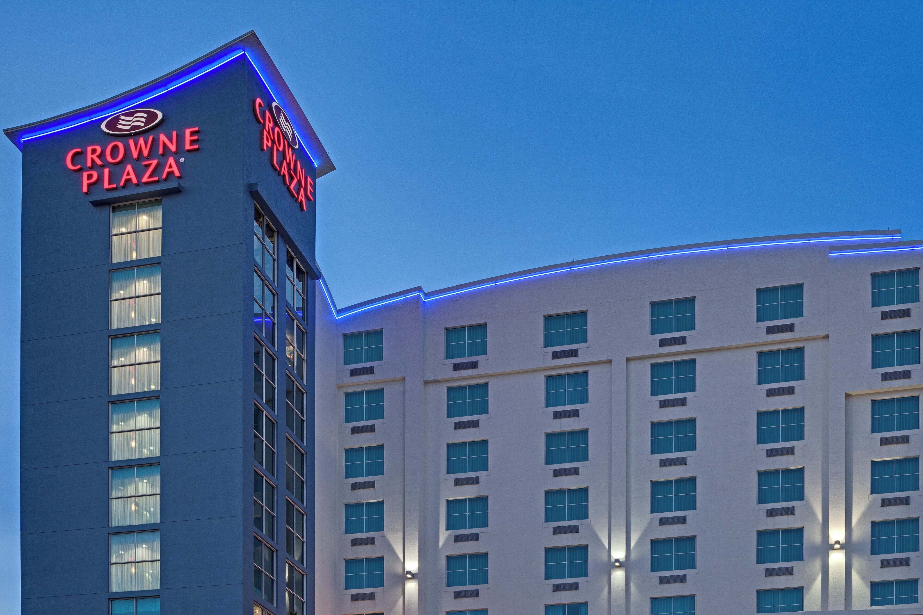 A hotel building with a prominent sign reading 'CROWNE PLAZA' and a modern architectural design.