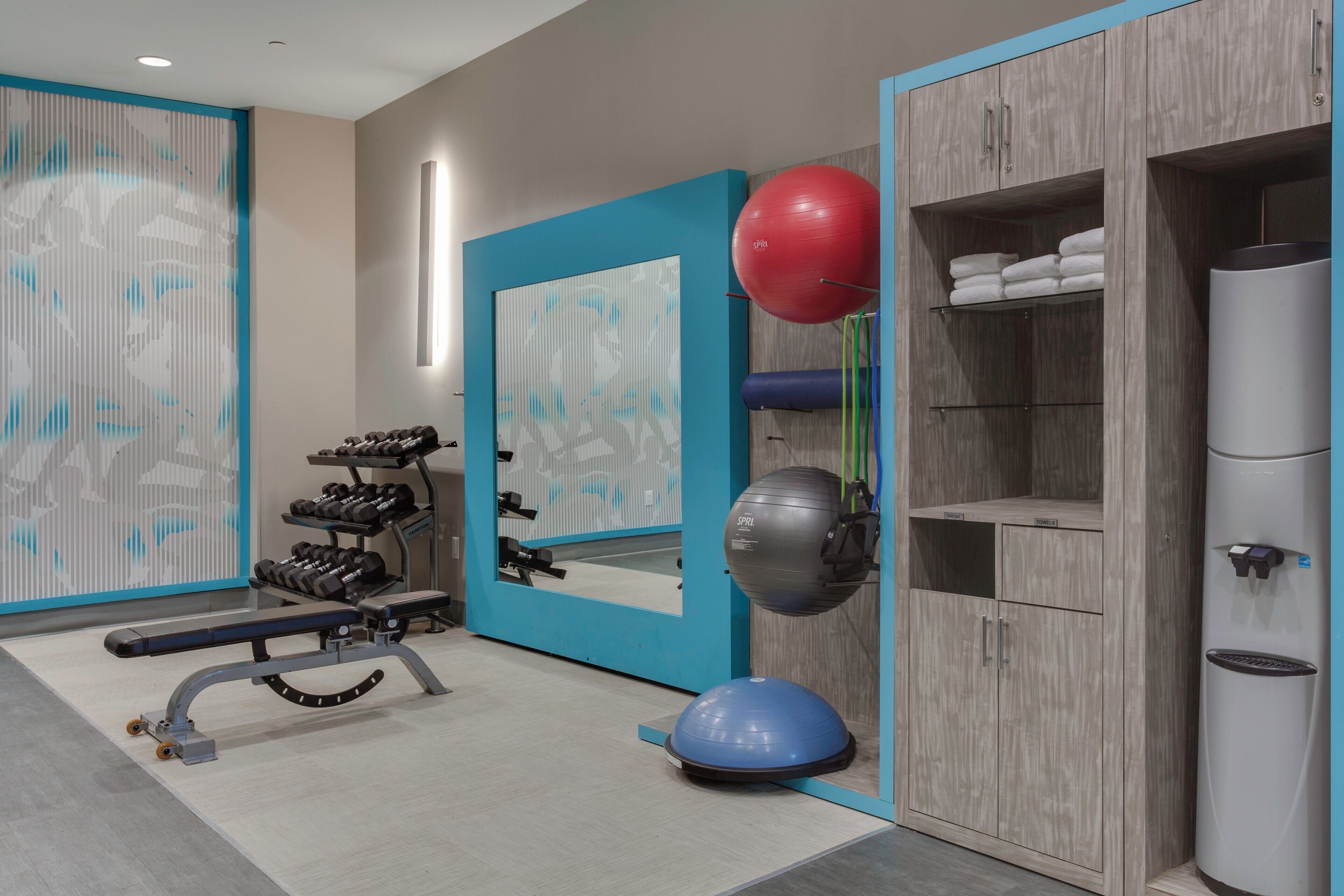 Un gimnasio con equipo de ejercicio, un espejo y un armario con estantes.