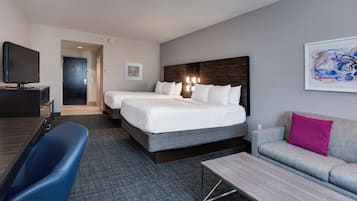 Una habitación de hotel con una cama grande, un escritorio con televisor de pantalla plana, un sofá y una mesita de centro.