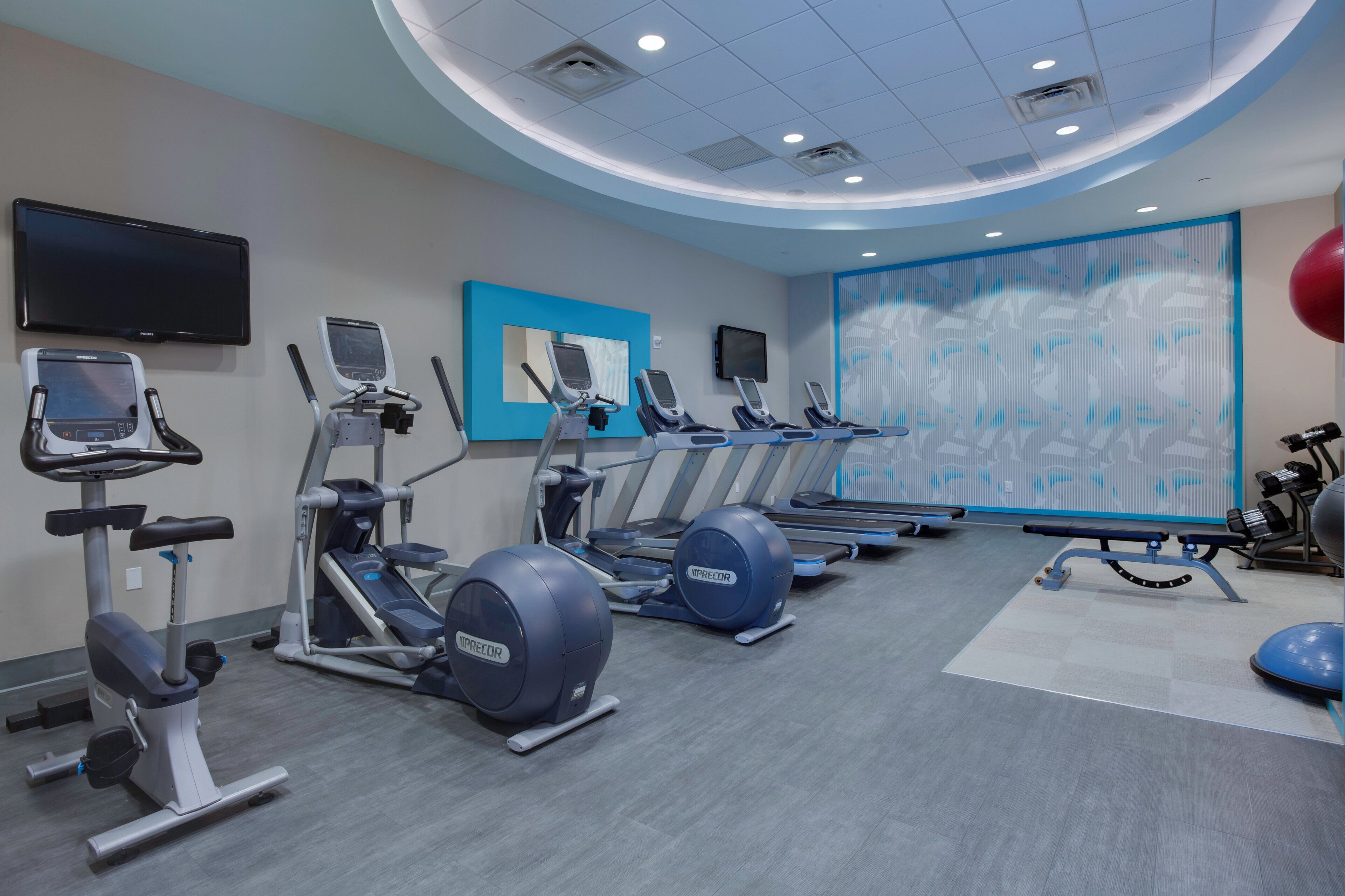 A gym with treadmills, ellipticals, and exercise balls.