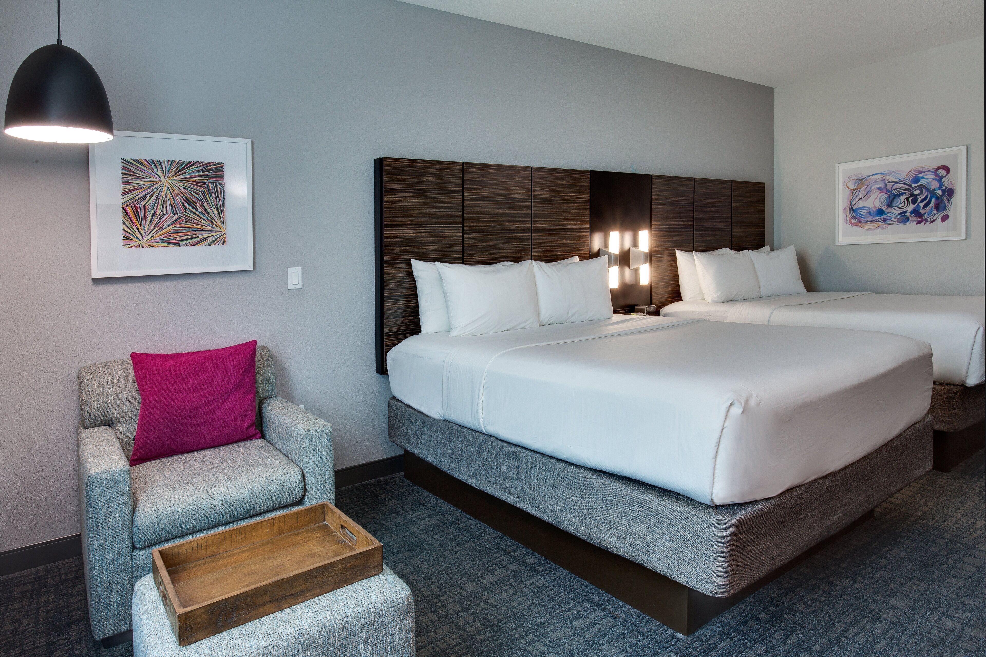 Ein Hotelzimmer mit einem großen Bett, einem Sessel, einem Holznachttisch und zwei Wandleuchten.