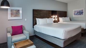 A hotel room with a large bed, a chair, a wooden side table, and two wall-mounted light fixtures.