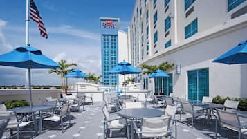 An outdoor patio area with tables and chairs, umbrellas, and an American flag.