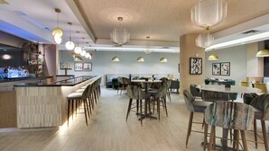 Ein modernes Restaurant mit Barbereich, runden Tischen und Barhocker.