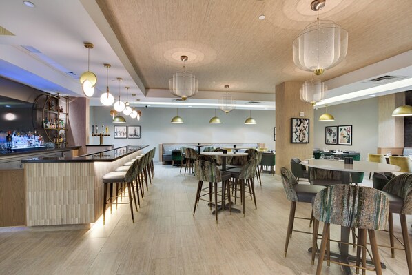 A modern restaurant with a bar area, round tables, and bar stools. - Crowne Plaza Hotel Fort Lauderdale Airport/Cruiseport by IHG (Fort Lauderdale)