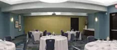Un salón de conferencias con mesas redondas, sillas y suelo alfombrado.