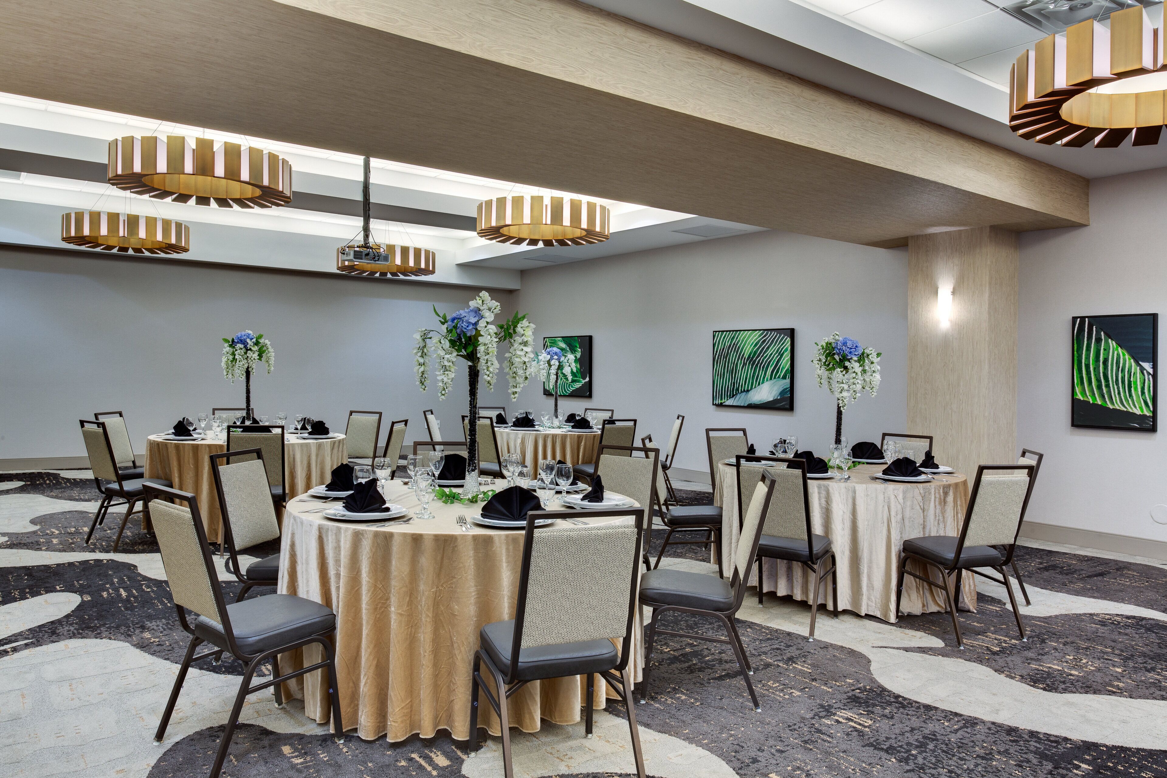 A conference room with round tables, chairs, and hanging pendant lights.