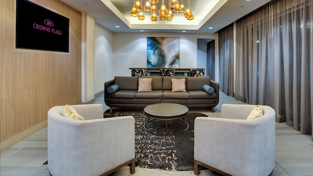 Un vestíbulo moderno con un conjunto de sofás, dos sillones, una mesa de centro y una pantalla grande que muestra