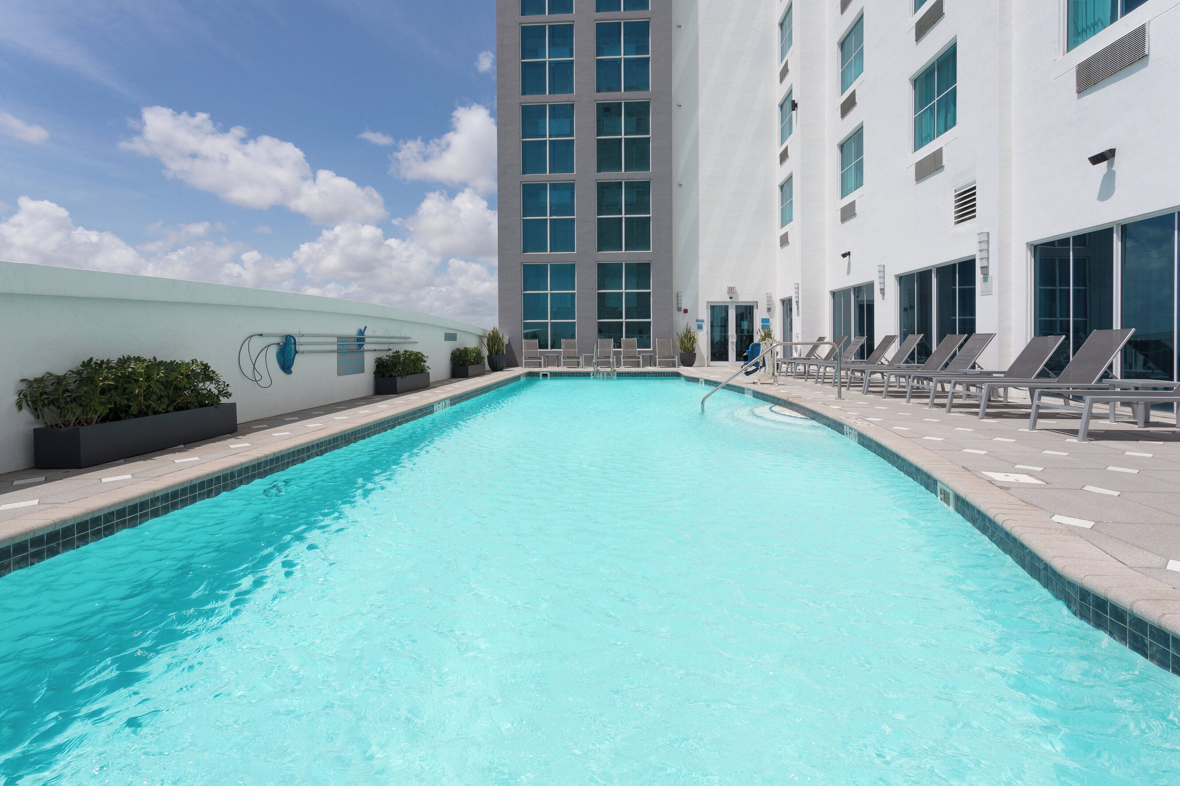 A swimming pool with lounge chairs and a modern building in the background.
