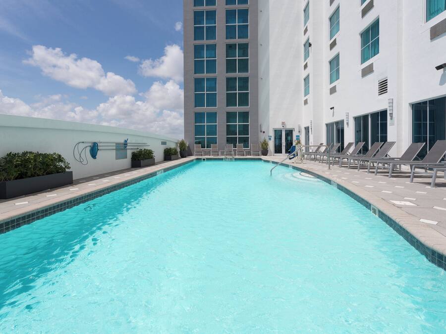 A swimming pool with lounge chairs and a modern building in the background.