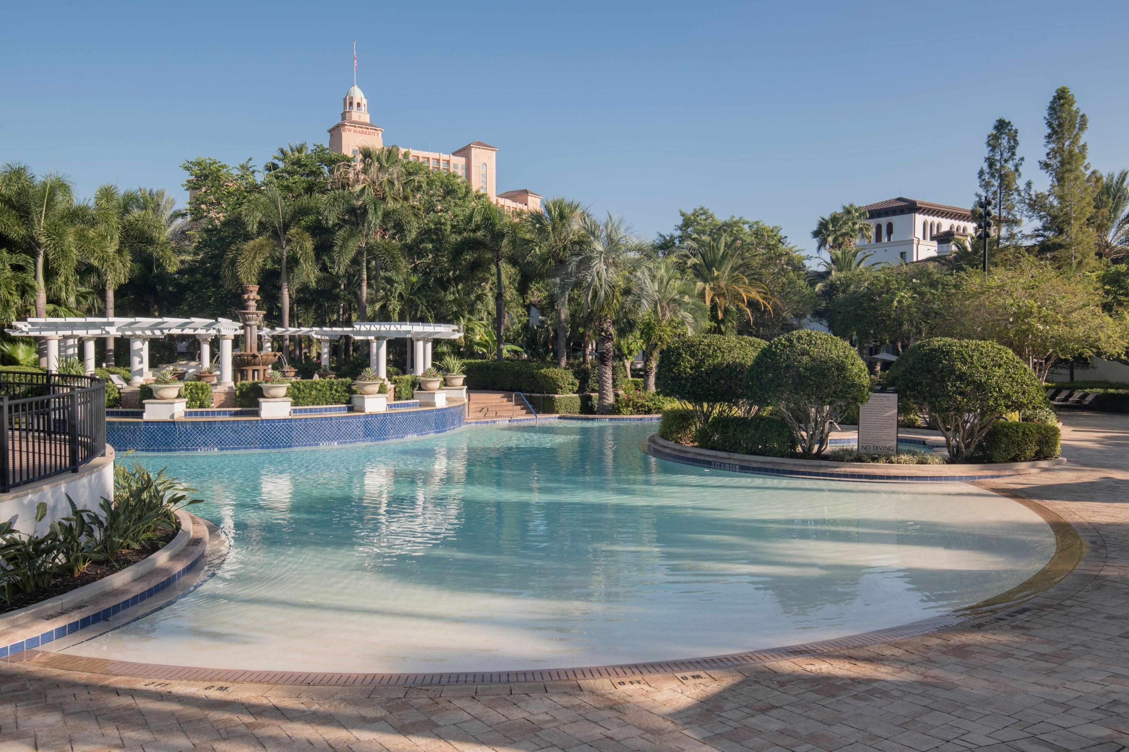 A swimming pool surrounded by palm trees and a gazebo.