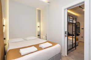 A hotel room with a large bed, a bedside table, a mirror, and a bunk bed in the adjacent room. - Istanbul Holiday Hotel (Istanbul)