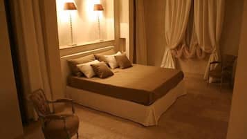 A bedroom with a large bed, two bedside lamps, a chair, and a window with curtains.